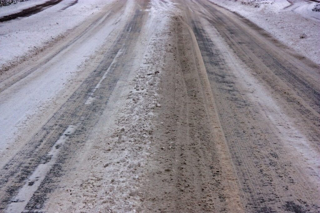 A road covered with slush and ice, the center line only barely visible